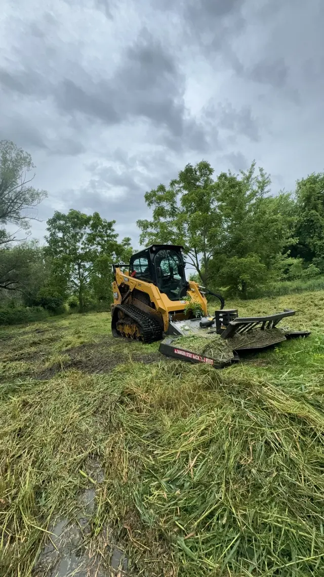 Skid steer with a brush cutter clearing tall grass