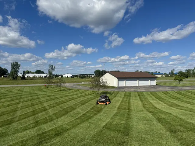 Large striped lawn being mowed with a riding mower