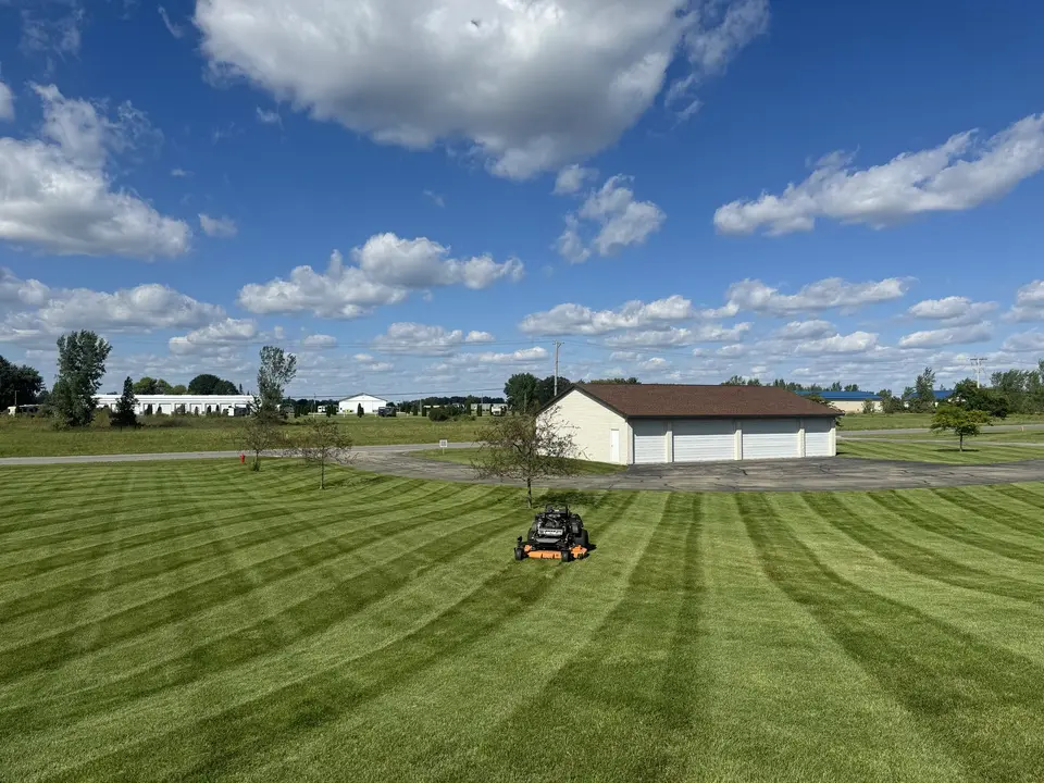 Large striped lawn being mowed with a riding mower